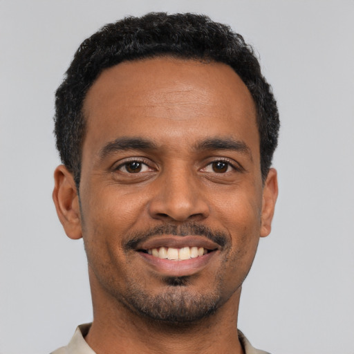Joyful black young-adult male with short  black hair and brown eyes