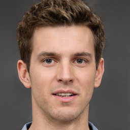 Joyful white young-adult male with short  brown hair and grey eyes