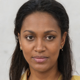 Joyful black young-adult female with long  brown hair and brown eyes