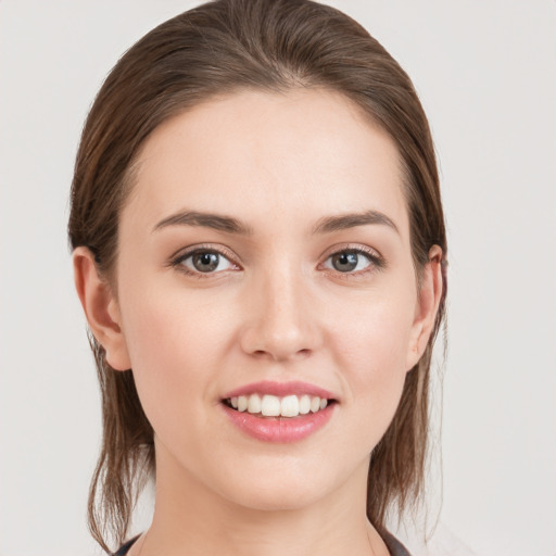 Joyful white young-adult female with medium  brown hair and grey eyes