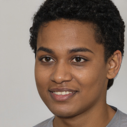 Joyful black young-adult female with short  black hair and brown eyes