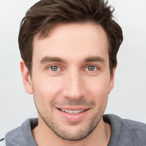 Joyful white young-adult male with short  brown hair and grey eyes