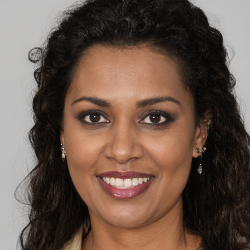 Joyful black young-adult female with long  brown hair and brown eyes