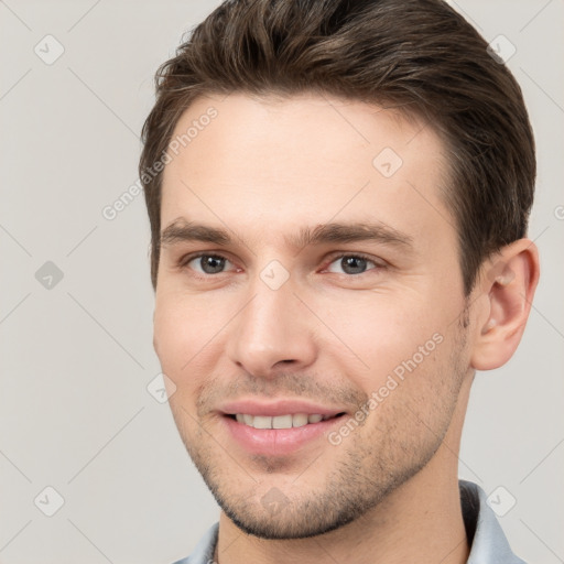 Joyful white young-adult male with short  brown hair and grey eyes