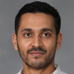 Joyful latino adult male with short  black hair and brown eyes