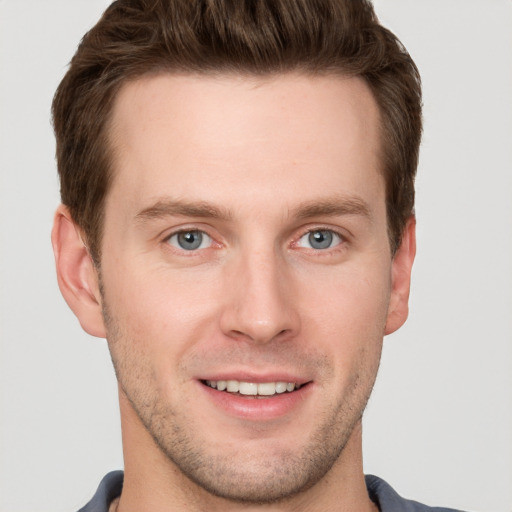 Joyful white young-adult male with short  brown hair and grey eyes