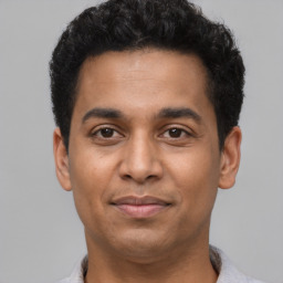 Joyful latino young-adult male with short  black hair and brown eyes