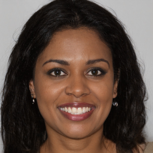 Joyful black young-adult female with long  brown hair and brown eyes