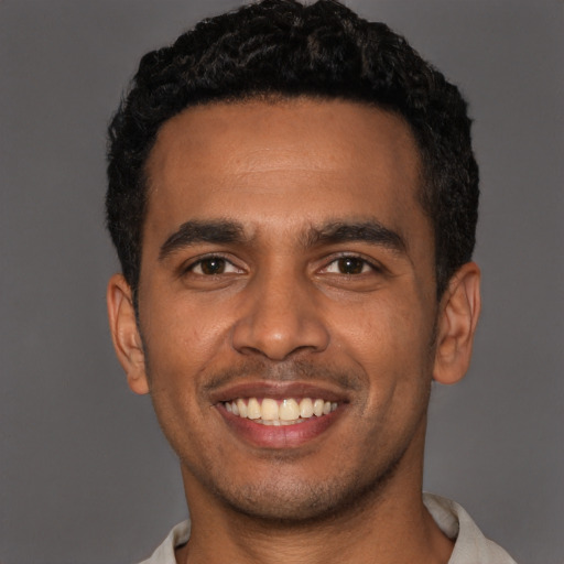 Joyful black young-adult male with short  black hair and brown eyes