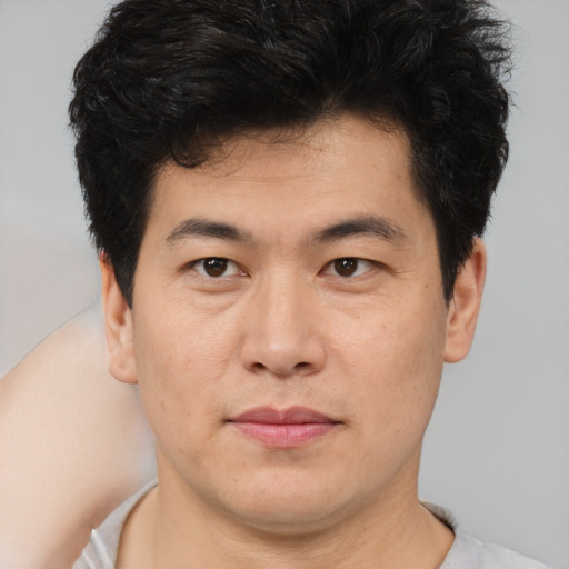 Joyful asian young-adult male with short  brown hair and brown eyes
