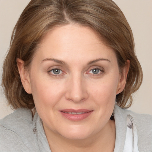 Joyful white adult female with medium  brown hair and blue eyes