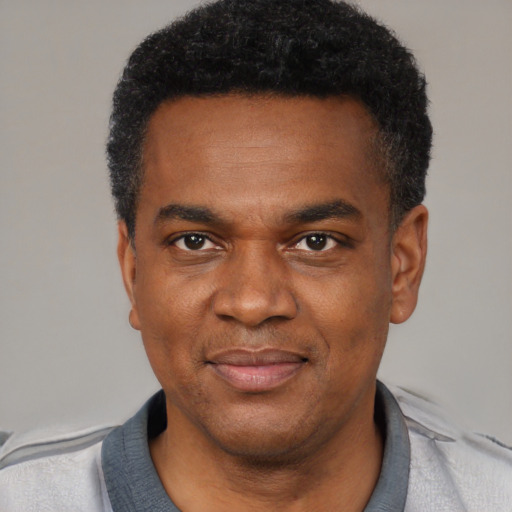 Joyful black young-adult male with short  black hair and brown eyes
