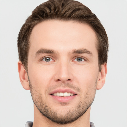 Joyful white young-adult male with short  brown hair and grey eyes