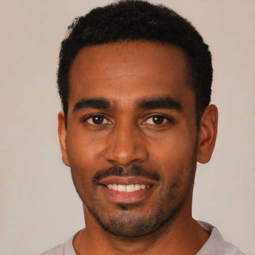 Joyful black young-adult male with short  black hair and brown eyes