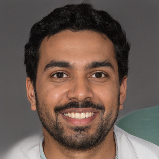 Joyful latino young-adult male with short  black hair and brown eyes