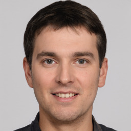 Joyful white young-adult male with short  brown hair and grey eyes