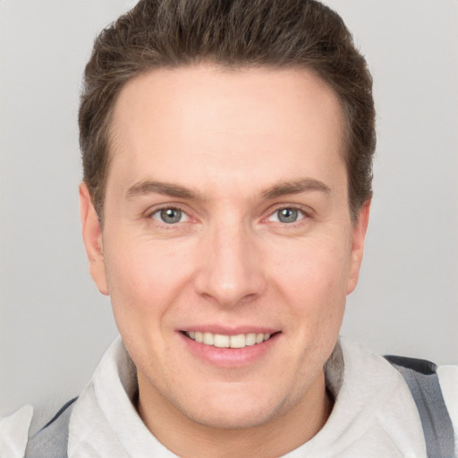 Joyful white young-adult male with short  brown hair and grey eyes