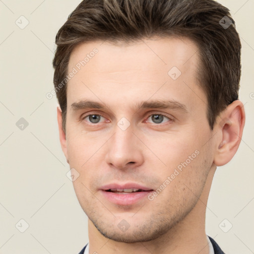 Joyful white young-adult male with short  brown hair and grey eyes