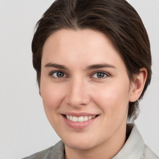 Joyful white young-adult female with medium  brown hair and grey eyes