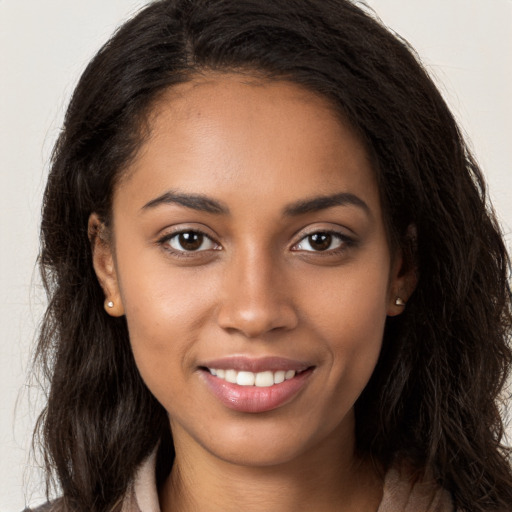 Joyful black young-adult female with long  brown hair and brown eyes