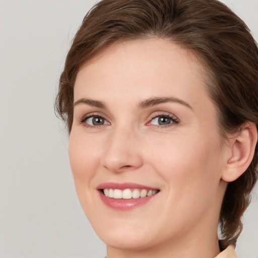 Joyful white young-adult female with medium  brown hair and grey eyes