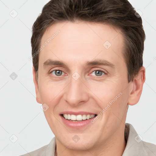 Joyful white young-adult male with short  brown hair and grey eyes