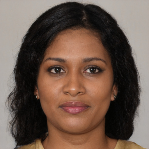 Joyful black young-adult female with long  brown hair and brown eyes
