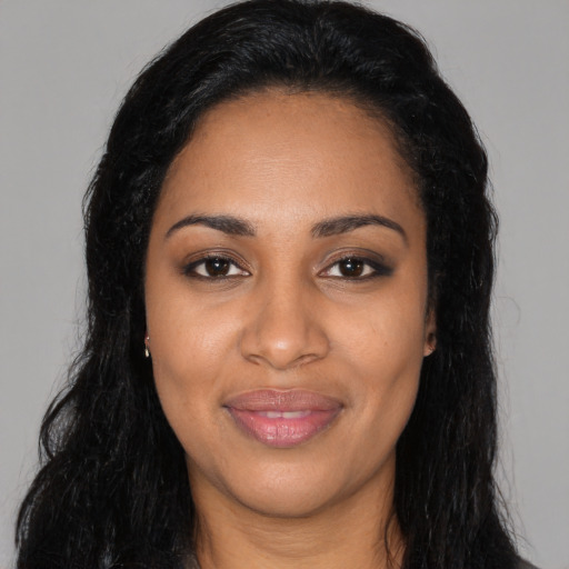 Joyful black young-adult female with long  black hair and brown eyes