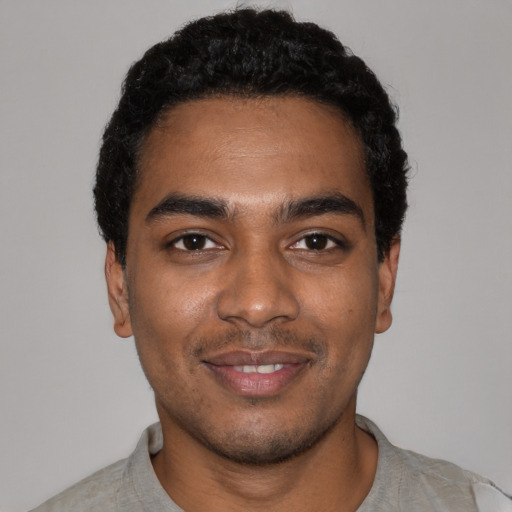 Joyful black young-adult male with short  black hair and brown eyes