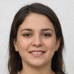 Joyful white young-adult female with long  brown hair and grey eyes