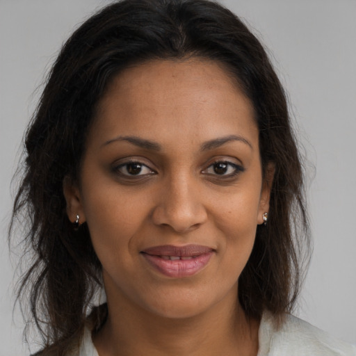 Joyful black young-adult female with long  brown hair and brown eyes