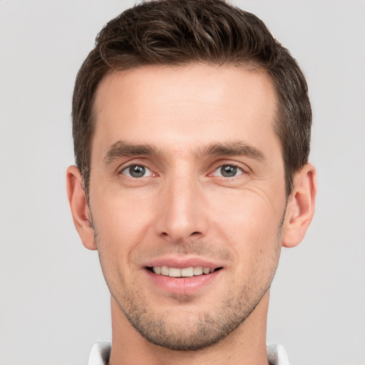 Joyful white young-adult male with short  brown hair and grey eyes