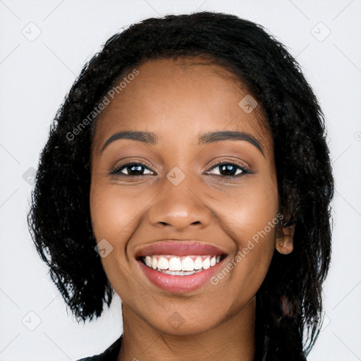 Joyful black young-adult female with long  black hair and brown eyes