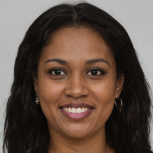 Joyful black young-adult female with long  brown hair and brown eyes