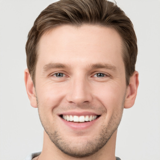 Joyful white young-adult male with short  brown hair and grey eyes