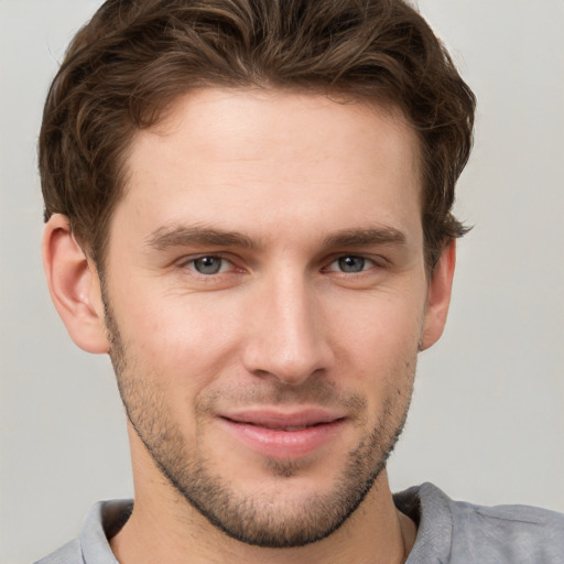 Joyful white young-adult male with short  brown hair and grey eyes