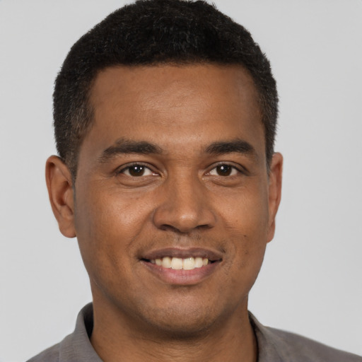 Joyful black young-adult male with short  brown hair and brown eyes