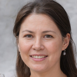 Joyful white adult female with long  brown hair and grey eyes