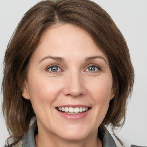 Joyful white adult female with medium  brown hair and grey eyes