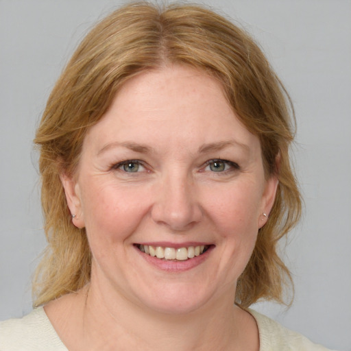 Joyful white adult female with medium  brown hair and blue eyes