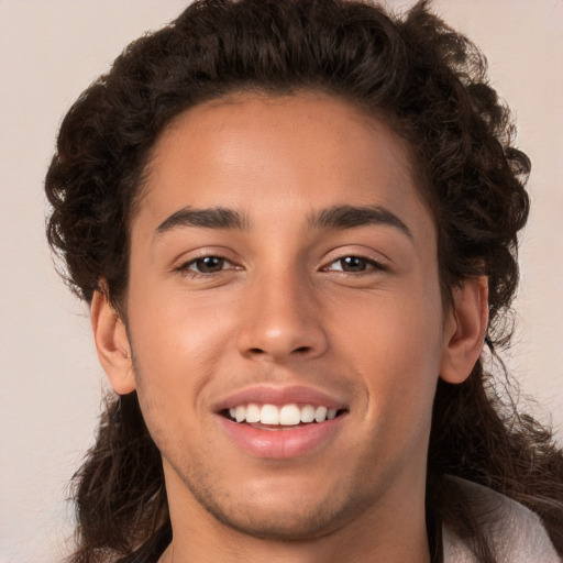 Joyful white young-adult male with long  brown hair and brown eyes