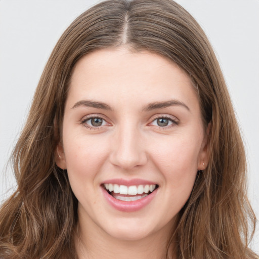 Joyful white young-adult female with long  brown hair and grey eyes