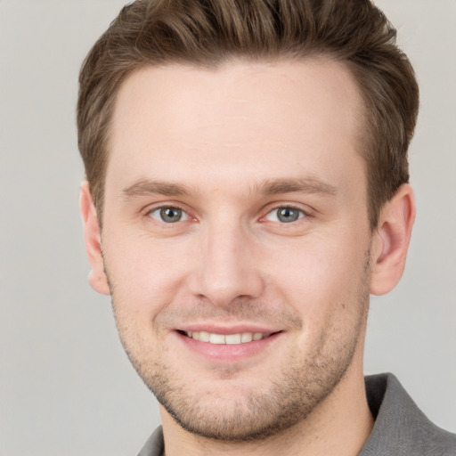 Joyful white young-adult male with short  brown hair and grey eyes