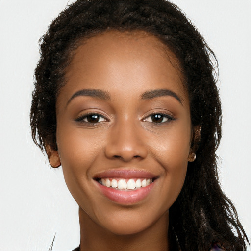 Joyful black young-adult female with long  brown hair and brown eyes