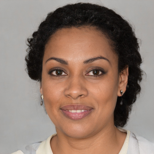 Joyful black young-adult female with short  black hair and brown eyes