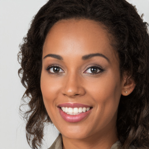 Joyful black young-adult female with long  brown hair and brown eyes