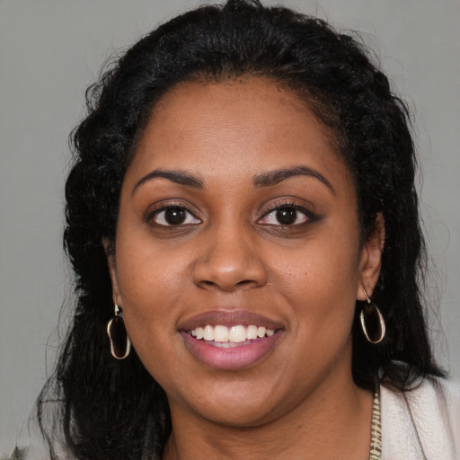 Joyful black young-adult female with long  brown hair and brown eyes