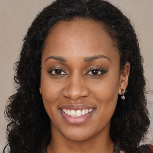 Joyful black young-adult female with long  black hair and brown eyes