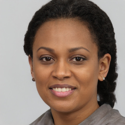 Joyful black young-adult female with short  black hair and brown eyes