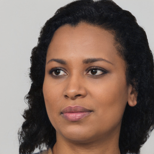 Joyful black young-adult female with long  black hair and brown eyes